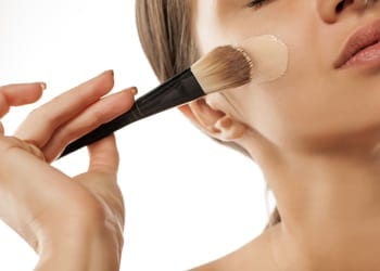 A bride applying her foundation makeup with a brush