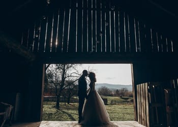 A bride and groom kissing under the archway of a barnyard door