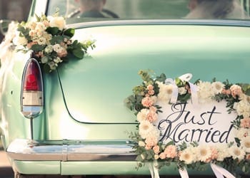 A vintage bridal car with a just married sign on the back