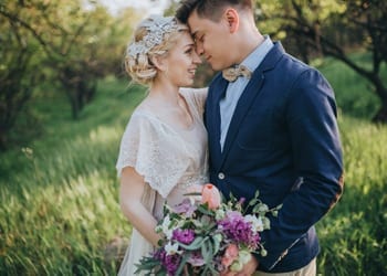 A happy bride and groom looking radiant in vintage style wedding day outfits