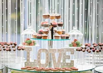 A cake pop and cupcake stand at a modern-themed wedding reception