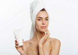 Lady with clean face holding skin care product 